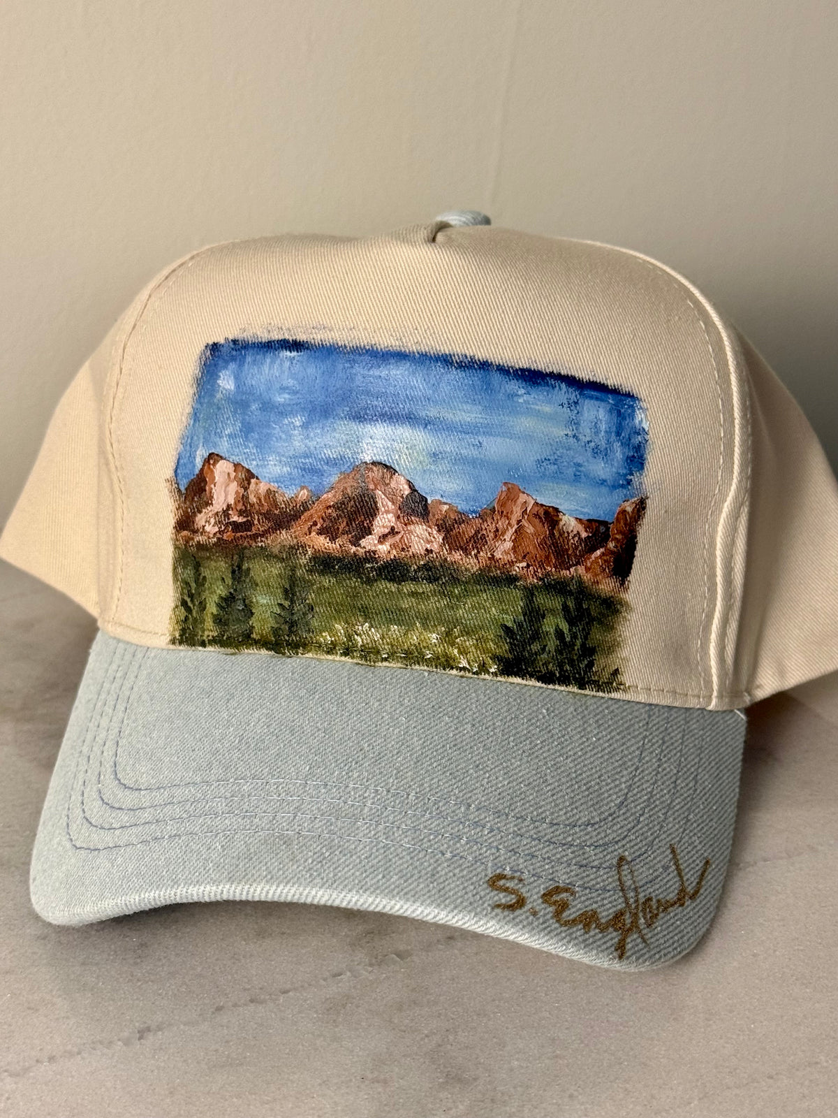 Hand painted wearable art on a soft cream and denim blue ball cap - mountain hikes