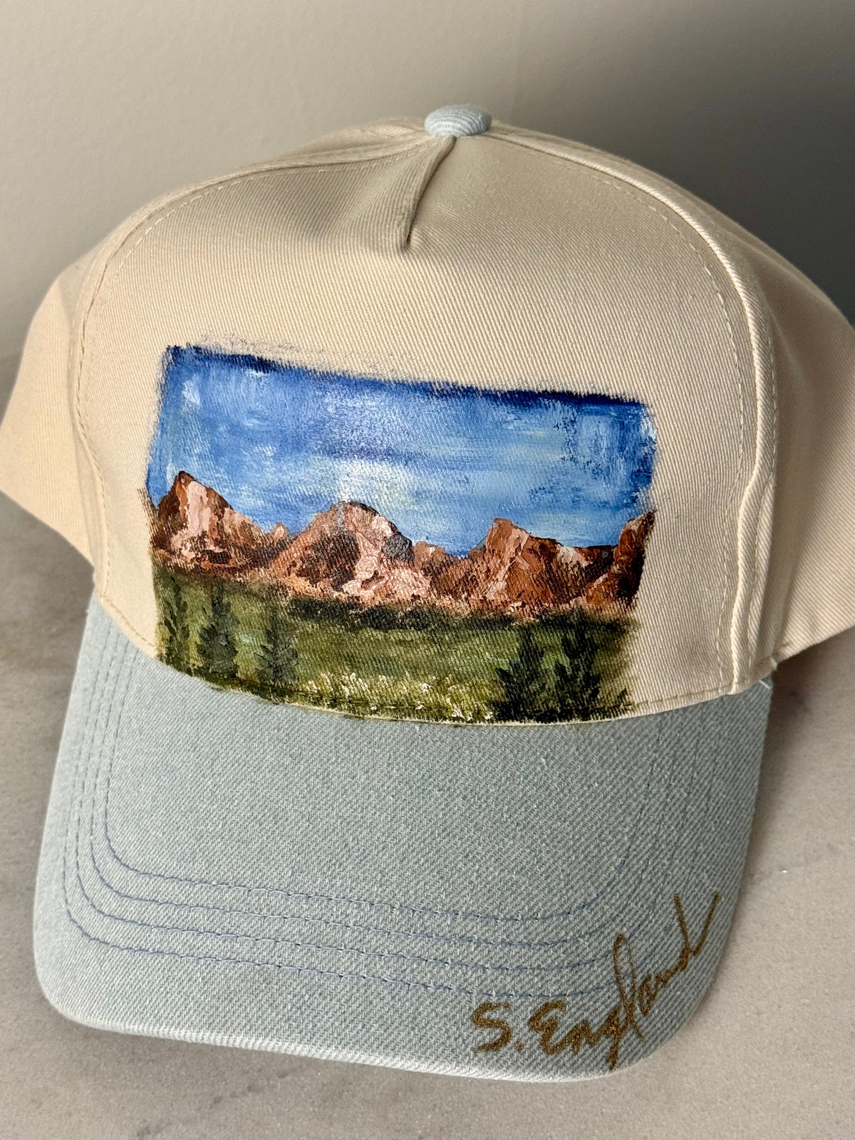 Hand painted wearable art on a soft cream and denim blue ball cap - mountain hikes