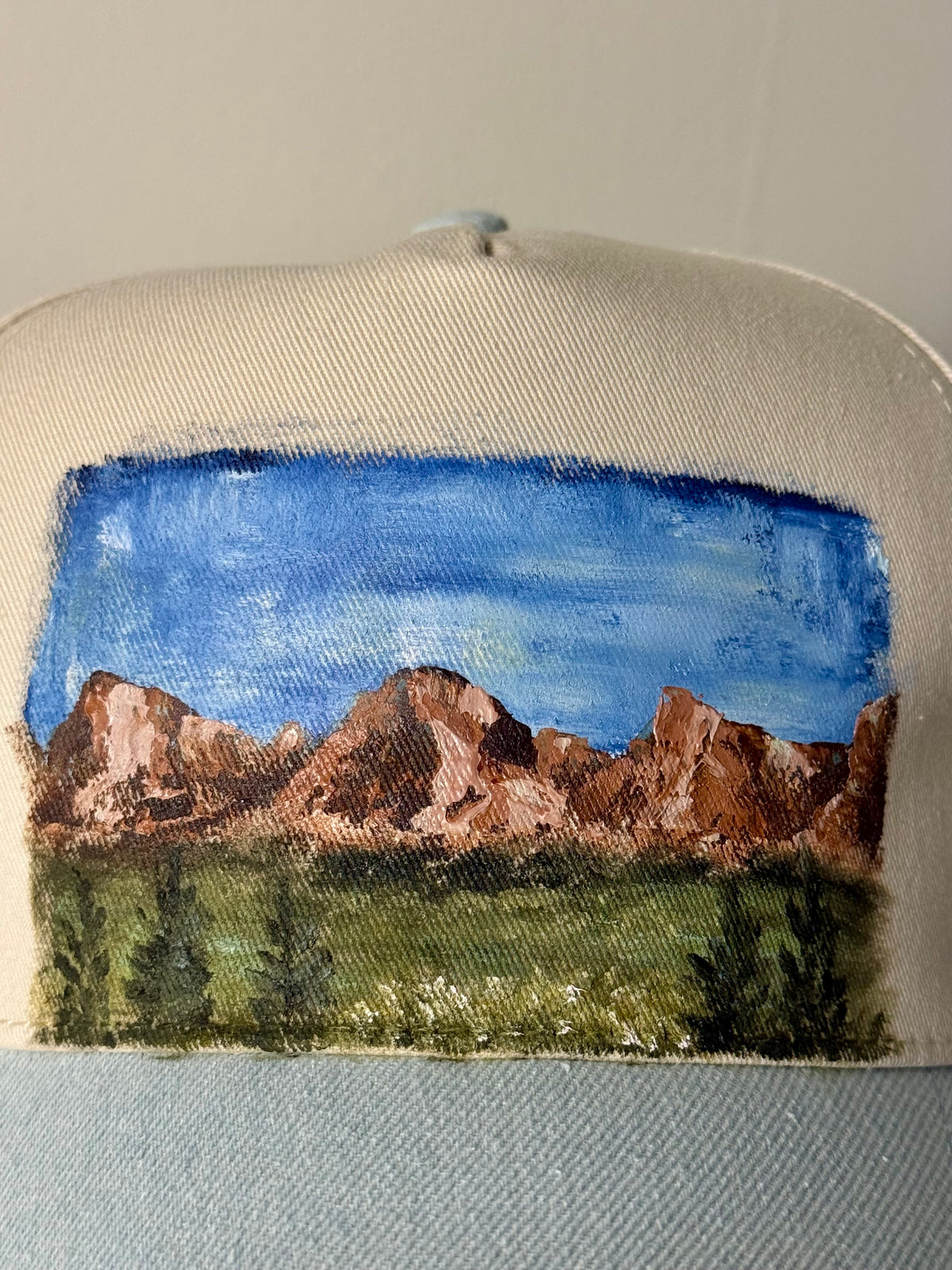 Hand painted wearable art on a soft cream and denim blue ball cap - mountain hikes